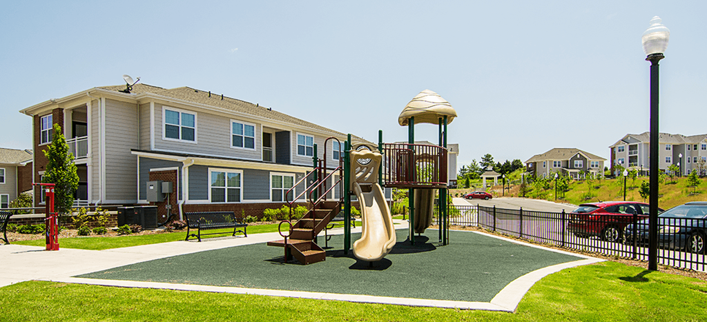 a playground with a slide in front of an apartment building at the lofts at southside