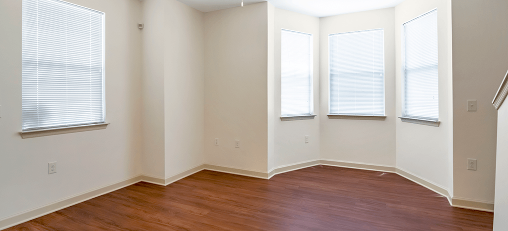 an empty living room with wood floors and three windows at The Lofts at Southside