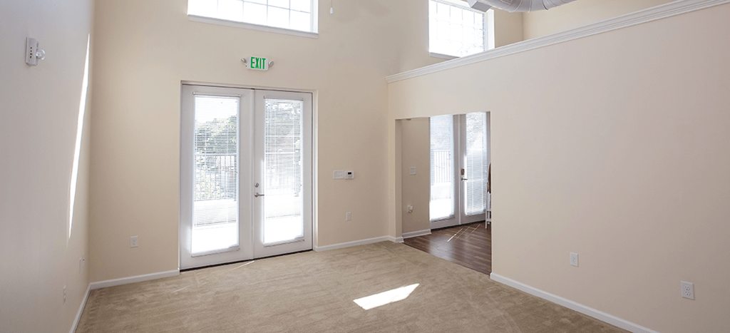 an empty bedroom with multiple windows and a door to a patio and entry to the living room area