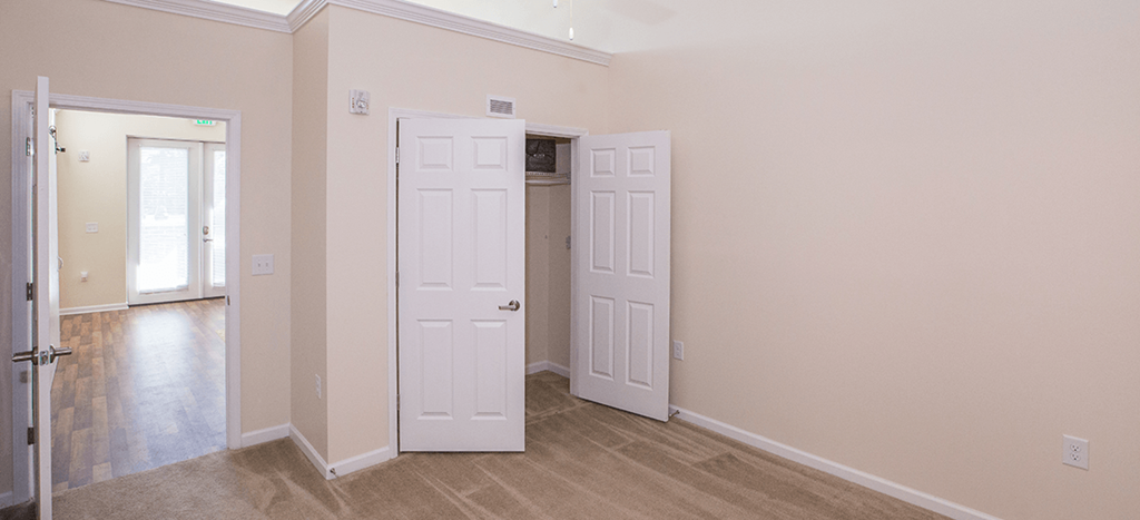 an empty bedroom and a closet with white doors