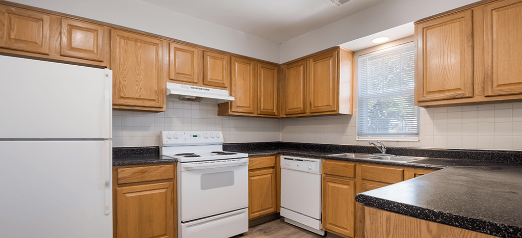 a kitchen with white appliances and wooden cabinets at Longfellow Heights apartments