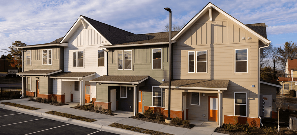 a row of Brown School Lofts with a sidewalk and a parking lot