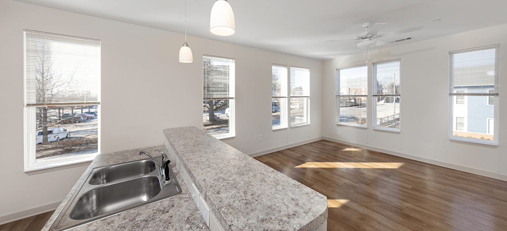 Brown School Lofts interior: an empty living room with a kitchen with a sink and windows