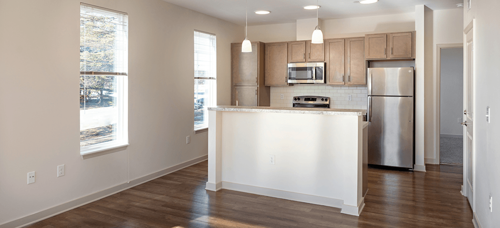 an empty kitchen with an island and a stainless steel refrigerator