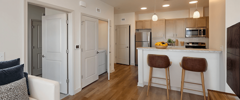 A kitchen with a white counter top and brown bar stools.