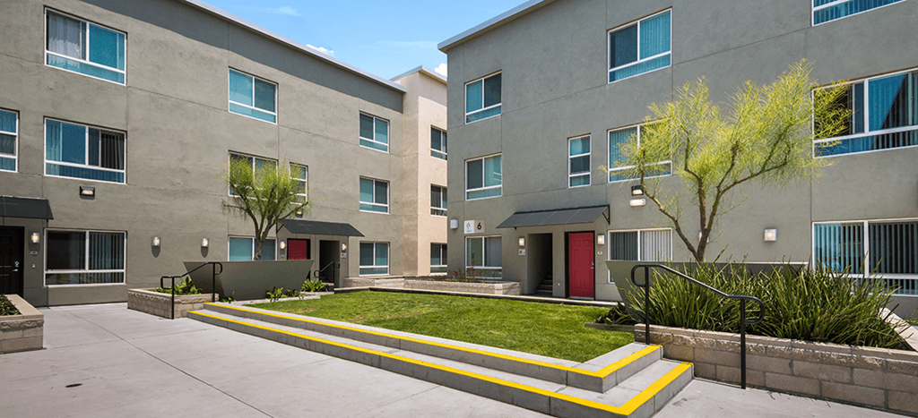 an exterior view of an apartment building with a yard and grass