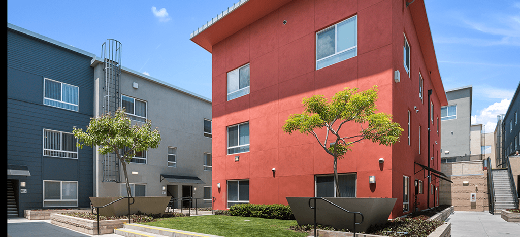 a red apartment building with a sidewalk in front of it