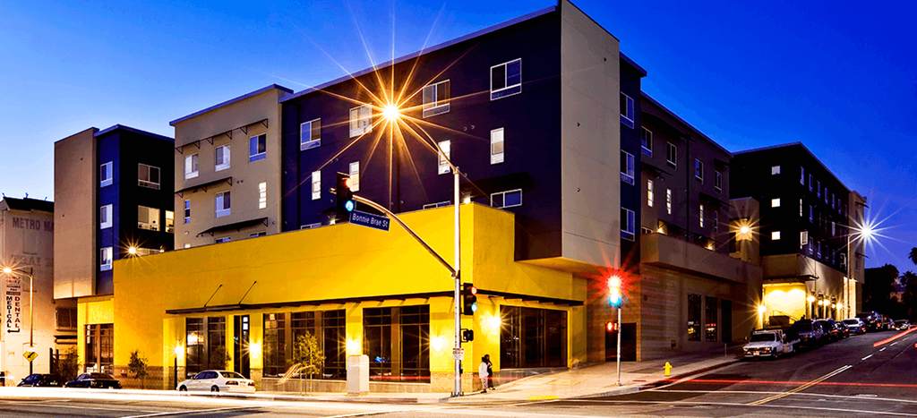 MacArthur Park Apartments building at night; a blue and yellow modern structure
