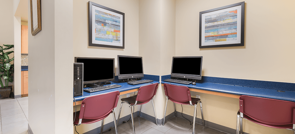 a computer room with four computers and chairs at MacArthur Park Apartments