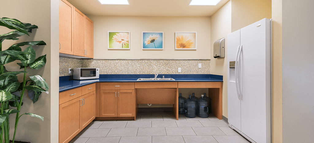 a kitchenette with a sink and a refrigerator and a blue counter top