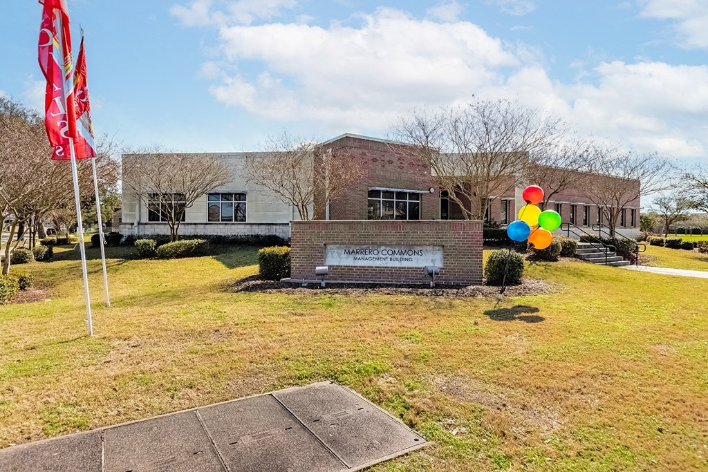 a building with balloons and a flag in front of it at Marrero Commons Apartments & Townhomes