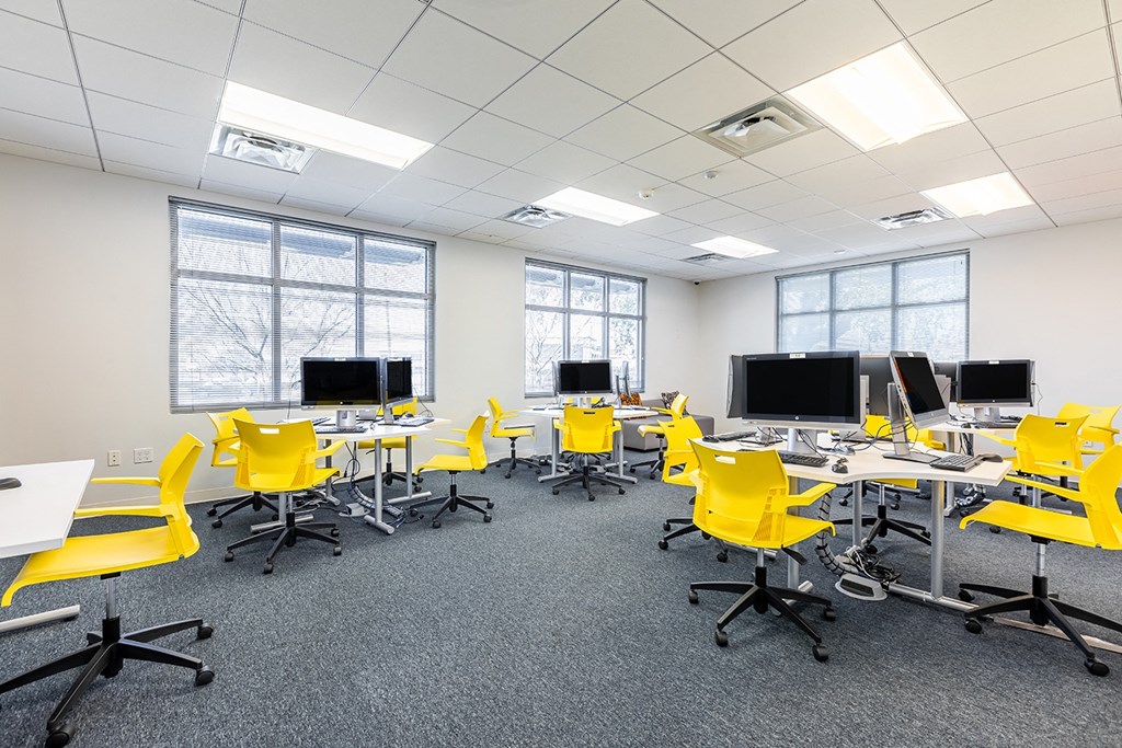 an empty business center with yellow chairs and desks and computers at Marrero Commons Apartments & Townhomes