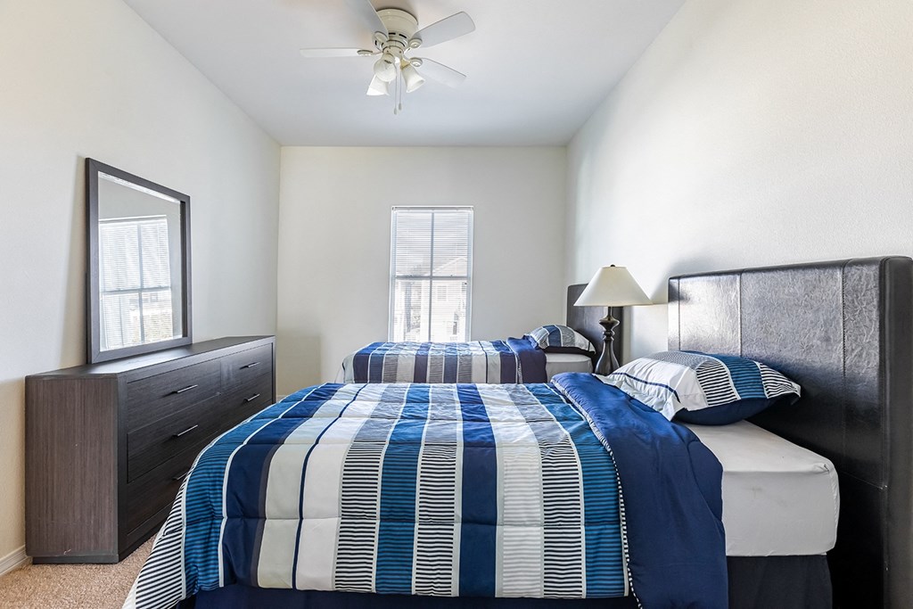 a bedroom with two beds and a ceiling fan at Marrero Commons Apartments & Townhomes