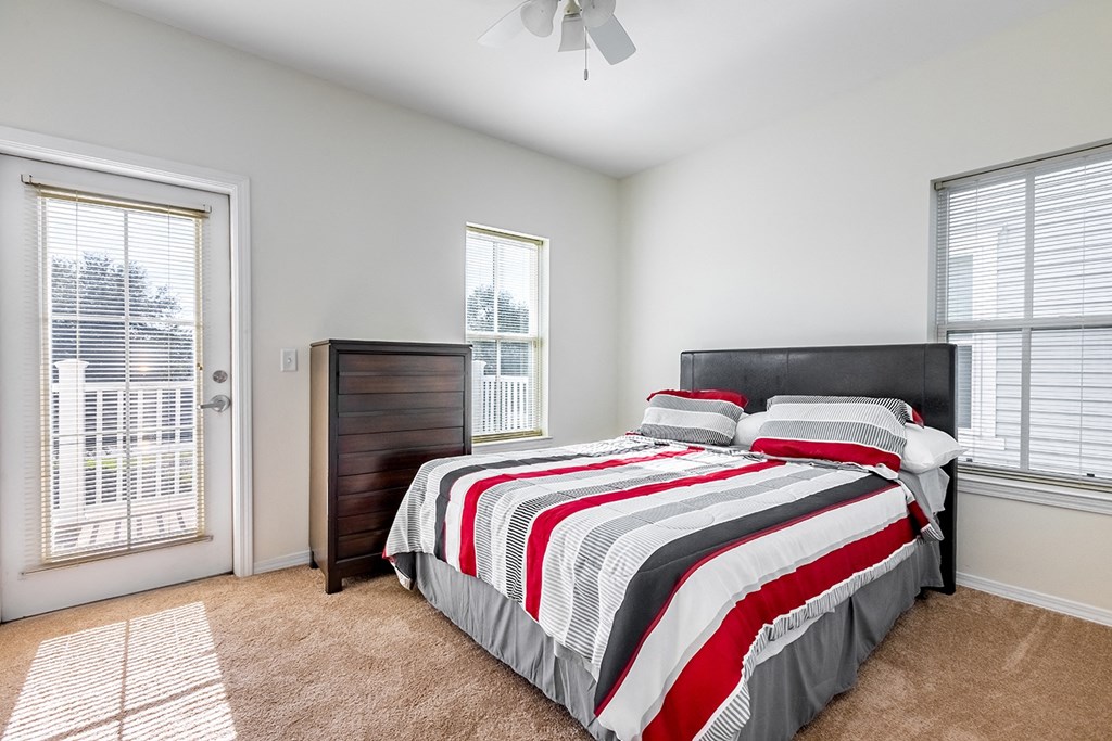 a bedroom with a bed and two windows at Marrero Commons Apartments & Townhomes