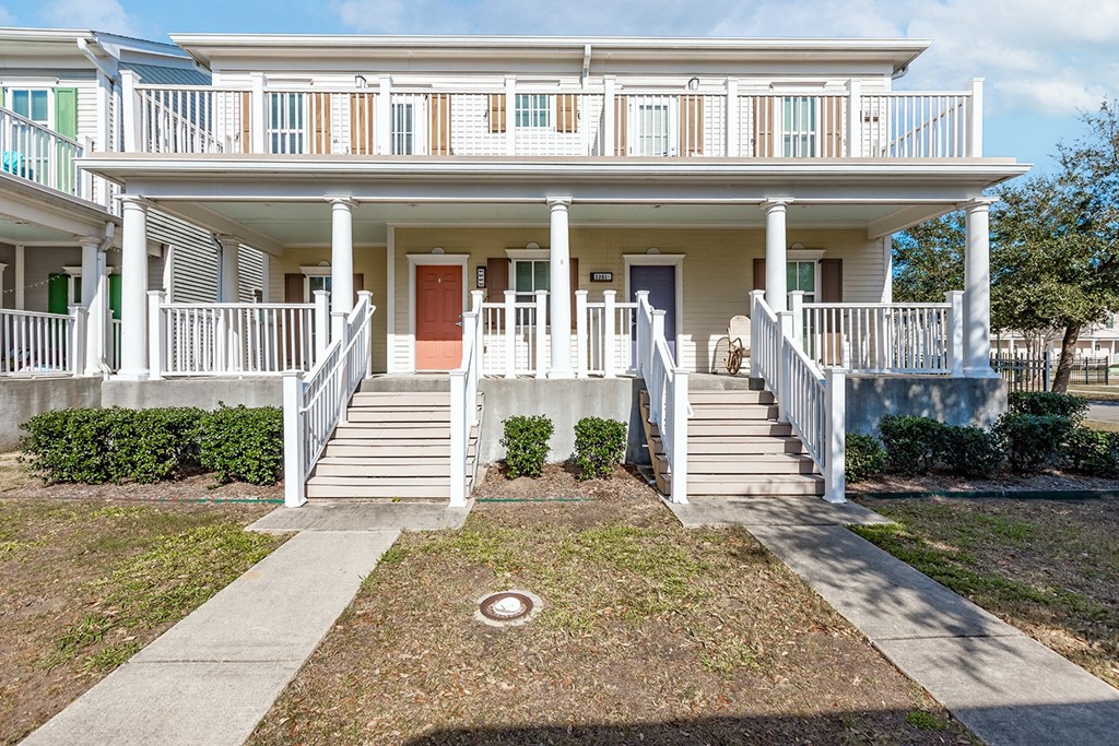 a white townhouse with a porch and stairs at Marrero Commons Apartments & Townhomes
