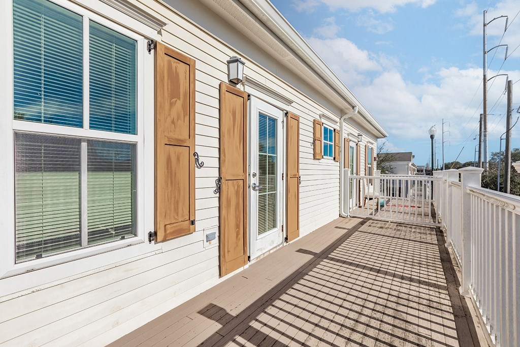 the front porch of a white house with wooden doors and windows at Marrero Commons Apartments & Townhomes