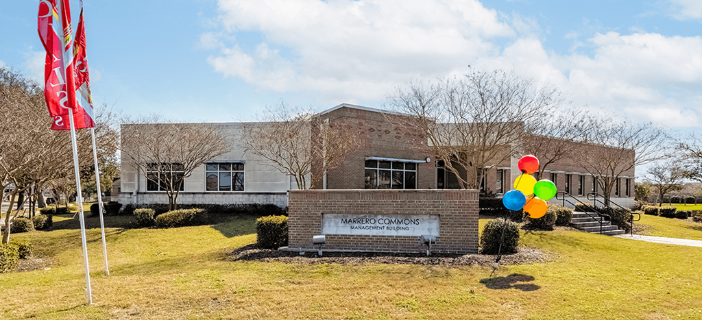 Marrero Commons Apartments leasing office with balloons in front and a flag