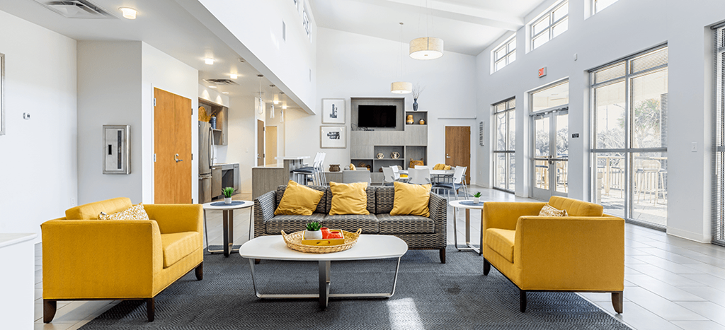 Marrero Commons Apartments clubhouse with yellow couches and chairs and a table