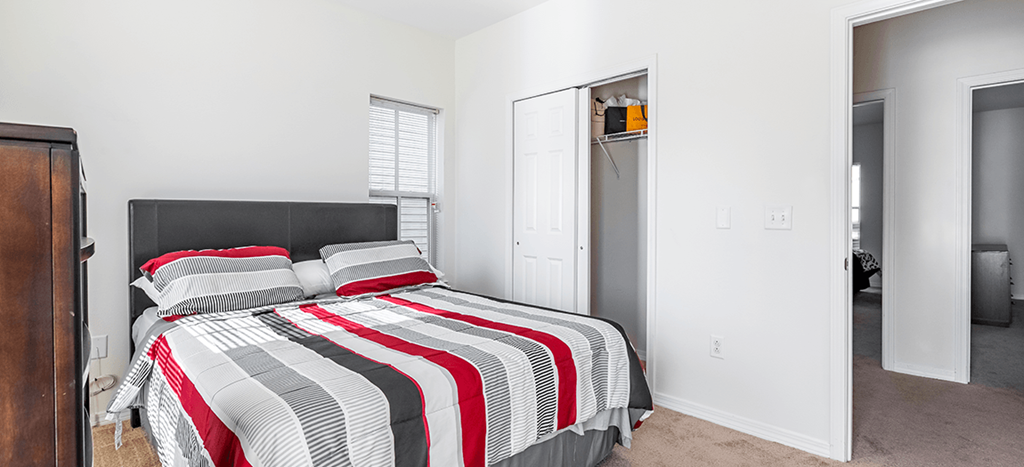 a bedroom with a bed and a closet at Marrero Commons Apartments