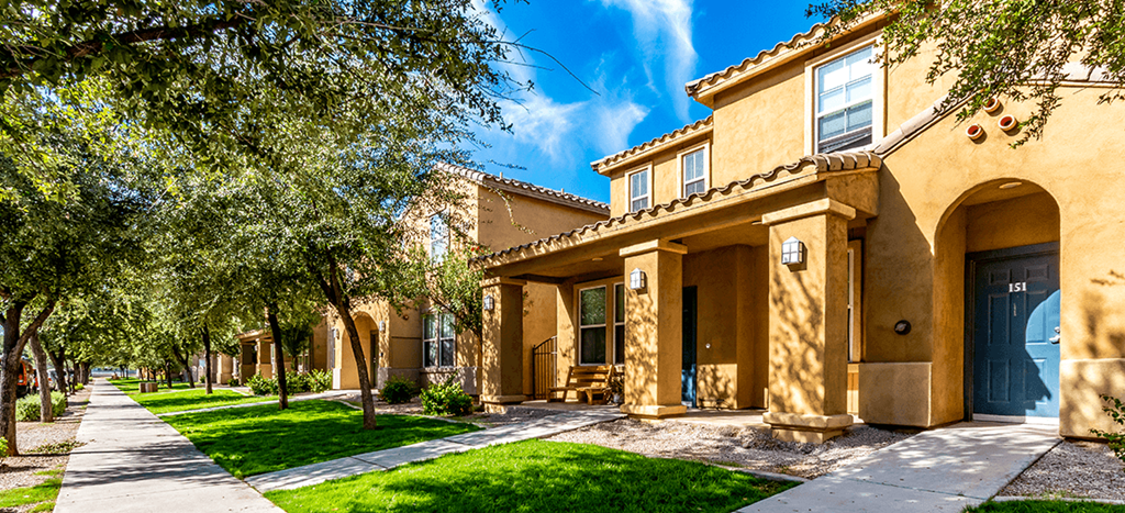 a yellow apartment home with trees and a sidewalk