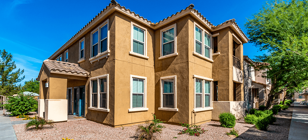 a large brown apartment home with trees and a blue sky