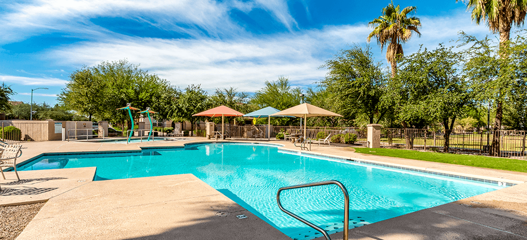 a swimming pool with umbrellas and chairs around it at Matthew Henson Apartments