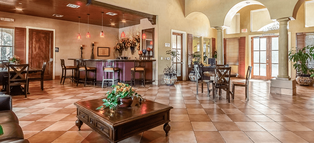 the lobby of Matthew Henson Apartments with tables and chairs and a bar