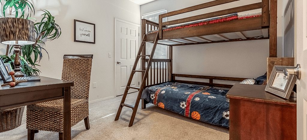 a bedroom with a bunk bed and a desk with a chair