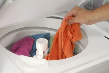 person putting clothes in washing machine-Legacy Apartments, Pittsburgh, PA 15219 - Photo Gallery 12