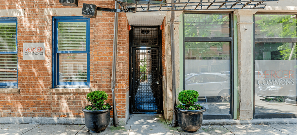 the front of a brick apartment building with an open door at Mercer Commons Apartments