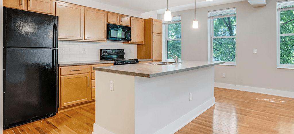a kitchen with an island and a black refrigerator at Mercer Commons Apartments