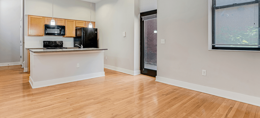 an empty kitchen and living room with wood flooring at Mercer Commons Apartments