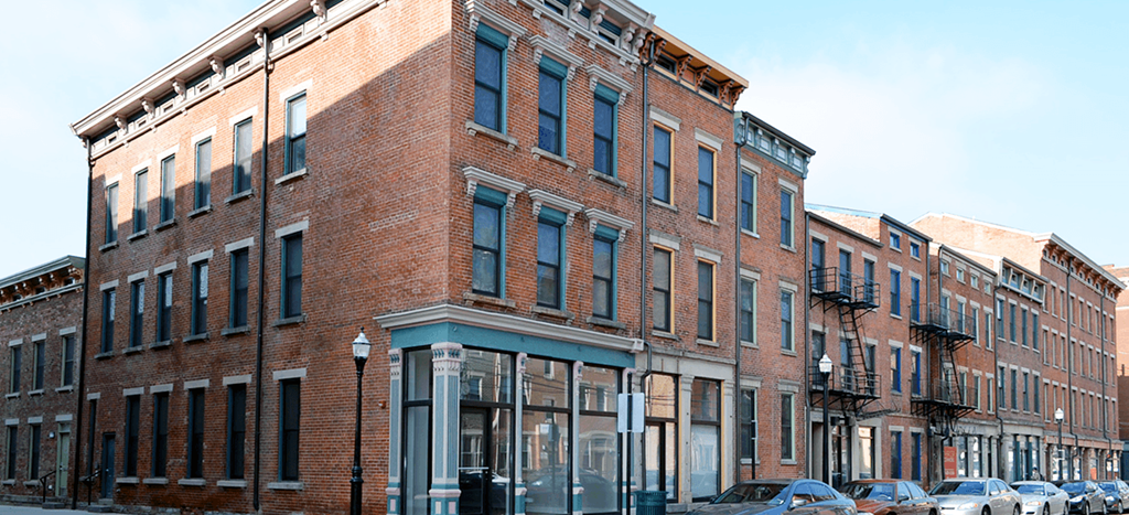 a large brick building with cars parked in front of it at Mercer Commons Apartments