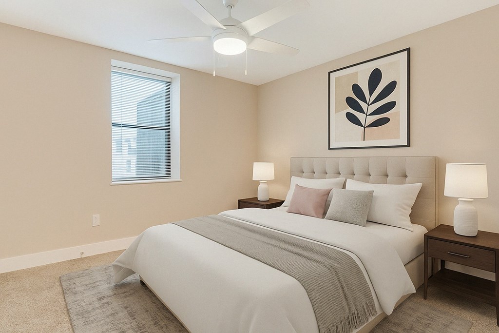 A bedroom with a large bed, two lamps, and a framed picture on the wall.