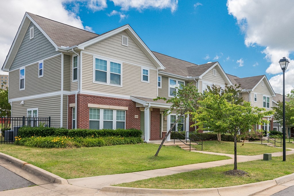 a row of houses on a street with grass and trees Cumberland Manor and Metropolitan Village Apartments and Townhomes in Little Rock, AR.