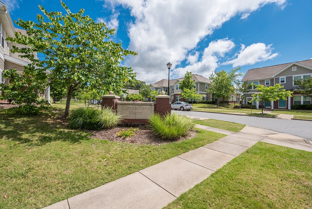 an entrance sign to a subdivision with townhouses on a street Cumberland Manor and Metropolitan Village Apartments and Townhomes in Little Rock, AR.