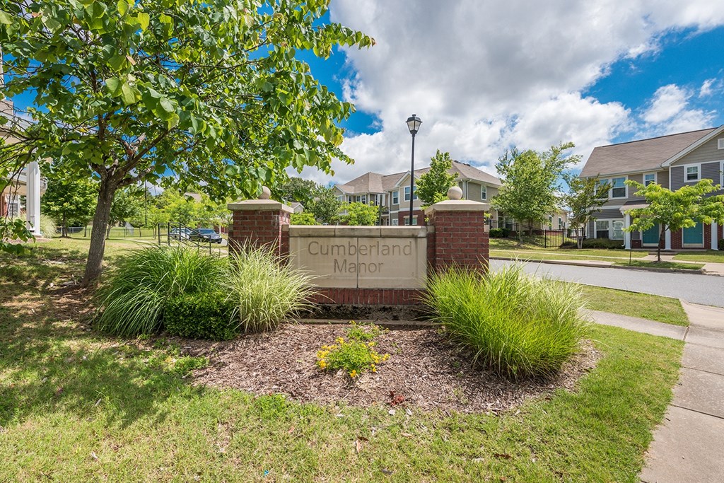 the sign is in front of a subdivision with trees and townhouses Cumberland Manor and Metropolitan Village Apartments and Townhomes in Little Rock, AR.