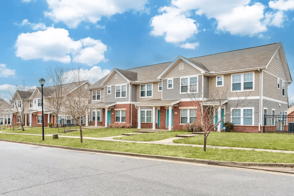 A row of houses with a blue sky and white clouds above them.