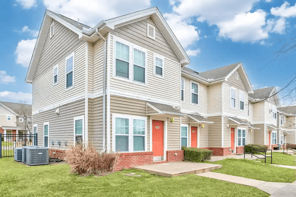 A large house with a red door and a green lawn.