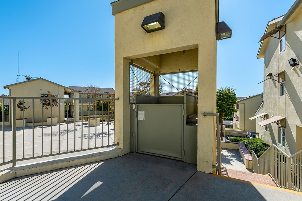 A gate with a metal railing and a small building with a black light on top.