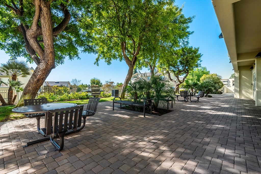 A patio with a table and chairs surrounded by trees.