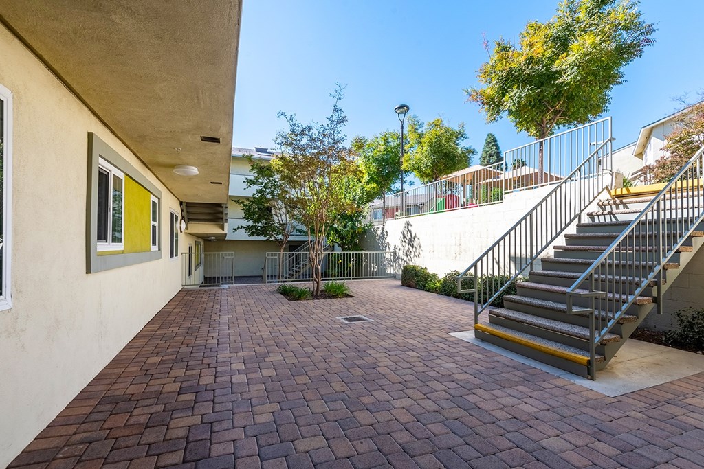 A courtyard with a staircase and a tree.