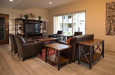 A living room with a brown leather couch, a wooden coffee table, and a television on a wooden stand.