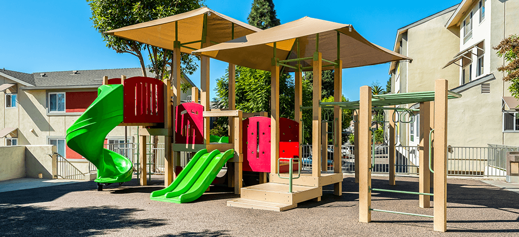 a childrens playground with slides and awnings at Mission Plaza Apartments