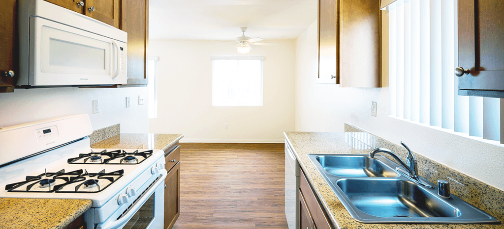 Mission Plaza Apartments; a kitchen with a stove and sink and a microwave