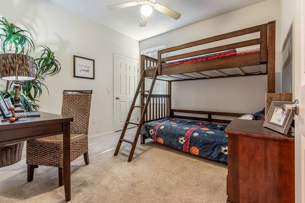 A room with a bunk bed, a desk, and a chair.