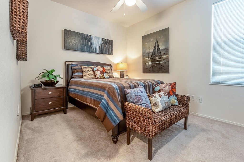 A bedroom with a bed, a bench, and a painting on the wall.