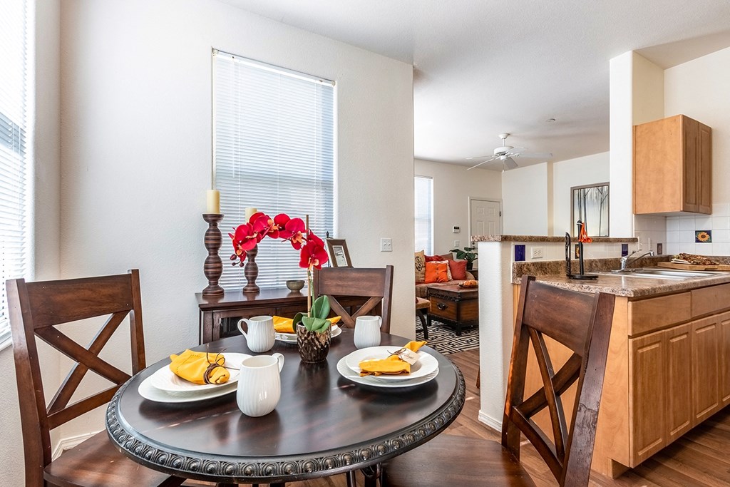 A dining room with a table set for two and a kitchen area in the background.