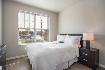 A bedroom with a large bed and a window overlooking a street.