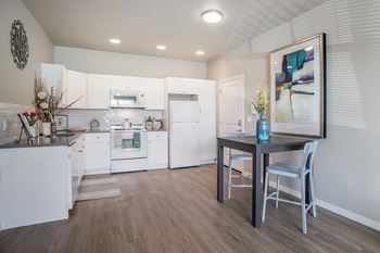 A kitchen with white cabinets and a wooden floor.